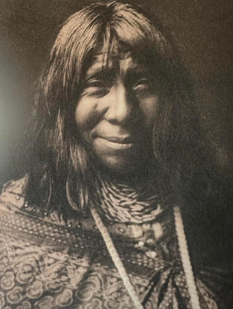 Indigenous woman with long dark hair, beaded necklace and patterned shawl — sepia portrait