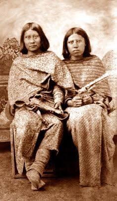 Sepia historical portrait of two Indigenous women seated together in traditional clothing