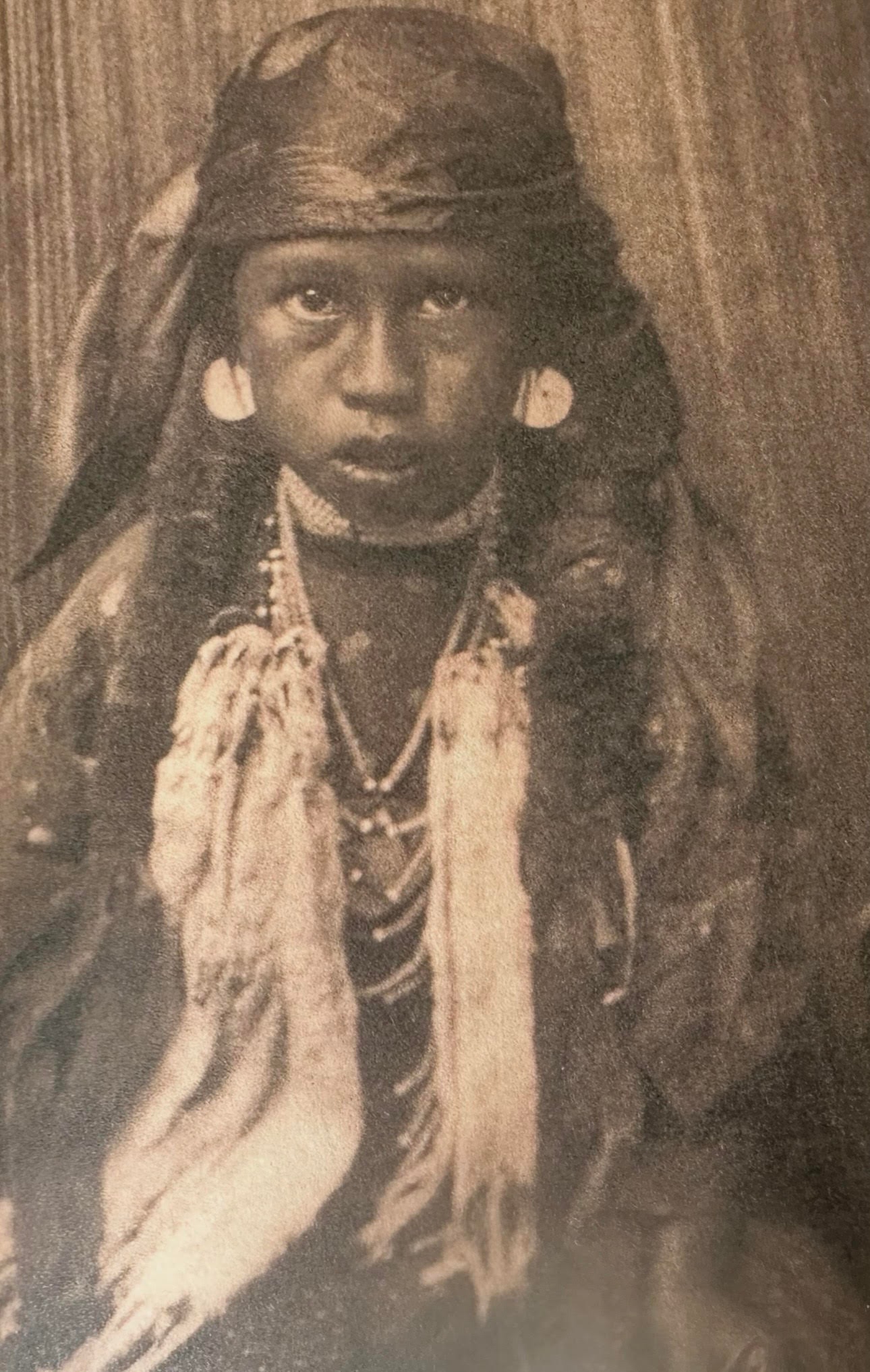 Indigenous North American child in traditional regalia with disc earrings